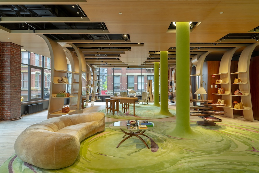 longchamp soho luxury retail store green carpet pillars brown rounded sofa curved wooden shelving